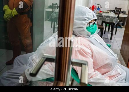 Bogor, Indonesien. August 2021. Nurhasanah macht eine Pause.Nurhasanah (37) ein Mitglied der Freiwilligen Polisi Masyarakat kümmert sich um einen behinderten Patienten, der verdächtigt wird, bei Covid-19 in Isolation zu sein. Lapor Covid-19, eine Koalition der Zivilgesellschaft, die Informationen über Coronaviren im ganzen Land zusammenstellt, berichtete über die Zahl der Covid-19-Todesfälle. (Foto: Wisnu Agung Prasetyo/SOPA IMAG/Sipa USA) Quelle: SIPA USA/Alamy Live News Stockfoto