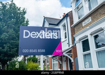 London - August 2021: Dexters Immobilienmakler 'verkauft' Schild vor Stadthäusern im Südwesten Londons Stockfoto