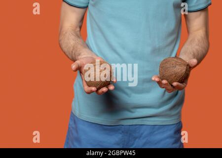 Zwei Kokosnüsse liegen auf den Handflächen von mans Stockfoto