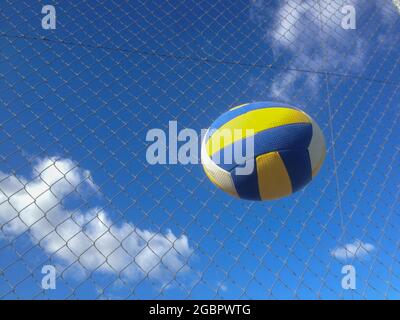 Volleyball Ball in der Luft über Drahtzaun Hintergrund. Bewegungsdeformierte Objekte Stockfoto