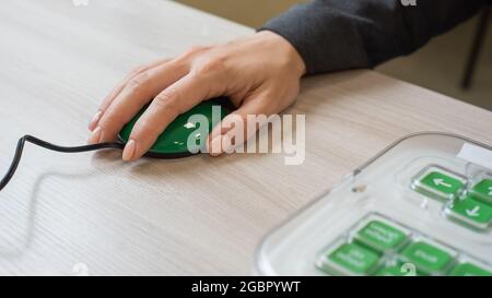 Eine Frau mit zerebraler Lähmung verwendet eine spezialisierte orgonomische Computermaus. Stockfoto