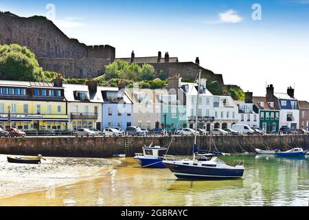 Gorey, Jersey, Channel Islands, GB - 7. Juli 2016: Boote und Yachten ankerten im Hafen, Gebäude am Meer im Hintergrund. Stockfoto