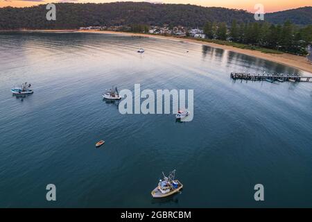 Fischerboote und Sonnenaufgang in Brisk Bay vom Patonga Beach an der Central Coast von NSW, Australien. Stockfoto