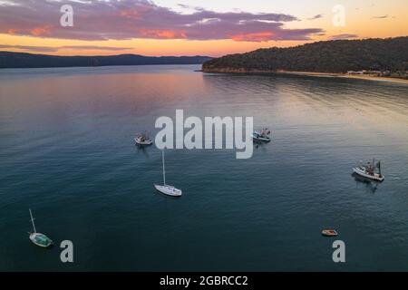 Fischerboote und Sonnenaufgang in Brisk Bay vom Patonga Beach an der Central Coast von NSW, Australien. Stockfoto