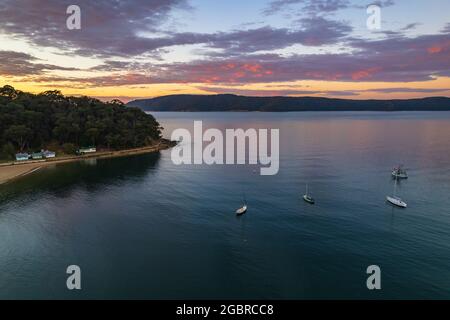 Fischerboote und Sonnenaufgang in Brisk Bay vom Patonga Beach an der Central Coast von NSW, Australien. Stockfoto