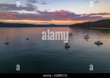 Fischerboote und Sonnenaufgang in Brisk Bay vom Patonga Beach an der Central Coast von NSW, Australien. Stockfoto