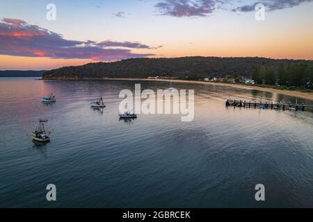 Fischerboote und Sonnenaufgang in Brisk Bay vom Patonga Beach an der Central Coast von NSW, Australien. Stockfoto