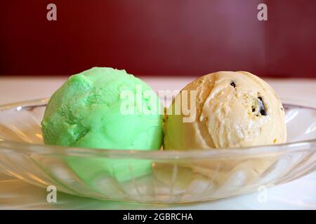 Nahaufnahme von zwei Kugeln Lime Sherbet und Chocolate Chip Ice Cream in einer Glasschüssel Stockfoto