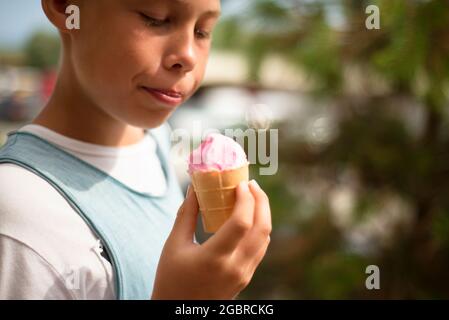 Der Junge hält ein rosa Eis in der Hand. Vergnügen. Positive Emotionen. Stockfoto