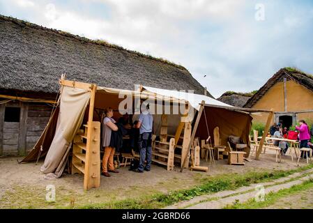 Schauspieler im mittleren Alter wikinger Kleidung Handwerk und Verkauf von traditionellen Holzmöbeln in Viking Haithabu Dorf gekleidet. Aufgenommen in Busdorf, Deutschland Stockfoto