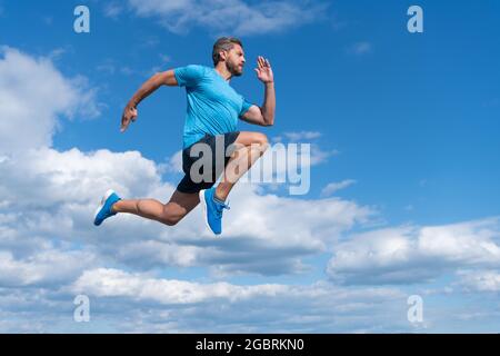 Energischer Mann Athlet mit muskulösen Körper laufen in Sportswear im Freien auf Himmel Hintergrund, Ausdauer Stockfoto
