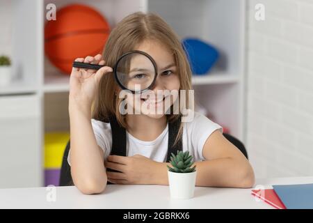 Untersuchen Sie mit Lupe. Wissenschaft und Kindheit. Teen Mädchen Blick auf die Pflanze durch Lupe Stockfoto