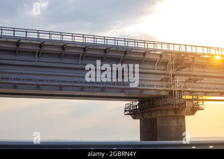 Stützen der Eisenbahnbrücke über die Kertschstraße bei Sonnenuntergang Stockfoto