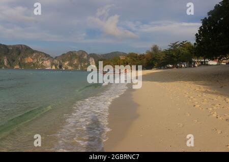 P, THAILAND - 16. Feb 2020: Schöner Sandstrand mit festgefahrenen Longtail-Booten im Hintergrund auf der Phi Phi Insel, Thailand Stockfoto