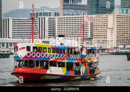 Der 'Night Star', eine der Star Ferry-Flotte, überquert den Victoria Harbour zum Tsim Sha Tsui Ferry Pier in Kowloon mit Ocean Terminal im Hintergrund Stockfoto