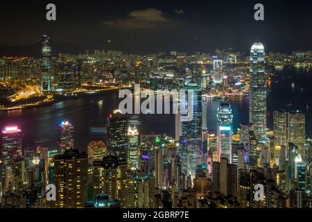 Die Wolkenkratzer und die hochdichte Stadtlandschaft der Midlevel und Central auf Hong Kong Island und Kowloon über den Victoria Harbour bei Nacht Stockfoto