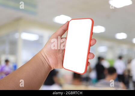 Handy in der Hand mit leerem Bildschirm auf Krankenhaushintergrund und haben Schnittpfade für Ihr Design. Stockfoto