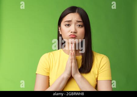 Nette unschuldige bedürftige asiatische Freundin bettelt Hilfe, Bitte um Gunst, ziemlich bitte, so dass Mitleid Gesicht zieht traurig Grimasse, runzelnd unglücklich, Hände halten Stockfoto