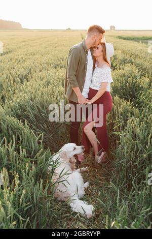 Schöne Momente des Glücks für ein trächtiges Paar in der Natur mit ihrem Hund. Familie und Schwangerschaft. Liebe und Zärtlichkeit. Glück und Gelassenheit. Nehmen Stockfoto