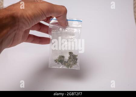 Ein Paket mit illegalem Cannabis in der Hand. Medizinisches Marihuana zur verschreibungspflichtigen Behandlung. Drogenhändler verkauft Marihuana-Süchtige. Stockfoto