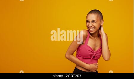 Porträt einer attraktiven jungen Frau mit kurzen Haaren, die den Kopierraum betrachtet. Stilvolles weibliches Modell auf gelbem Hintergrund. Stockfoto