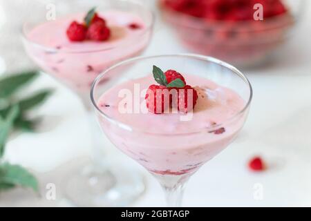 Köstliches italienisches Himbeer-Dessert, Käsekuchen, Maus im Glas auf weißem Hintergrund. Sommerlicher, gesunder Joghurt Stockfoto