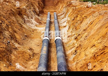 Installation der Verteilungseinheit des Heiz- und Wasserversorgungsnetzes. Rahmen für die Verbindung von Rohren im Erdgraben. Stockfoto