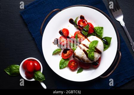 Gesundes Lebensmittelkonzept rustikaler Caprese Salat auf schwarzem Hintergrund mit Kopierfläche Stockfoto