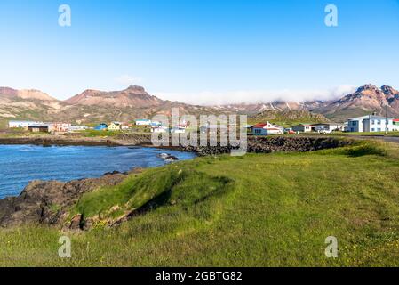 Kleines Fjorddorf am Fuße der aufragenden Berge in Island an einem klaren Sommertag Stockfoto