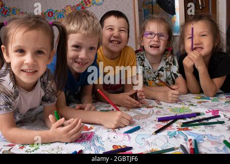 Fünf Kinder lachen und malen zusammen Stockfoto