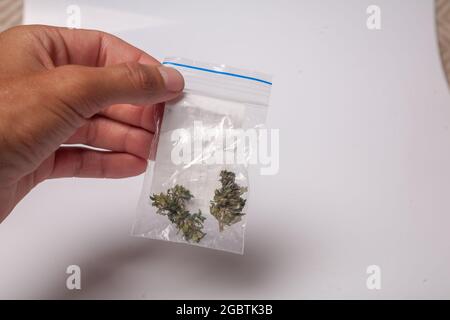 Ein Paket mit illegalem Cannabis in der Hand. Medizinisches Marihuana zur verschreibungspflichtigen Behandlung. Drogenhändler verkauft Marihuana-Süchtige. Stockfoto