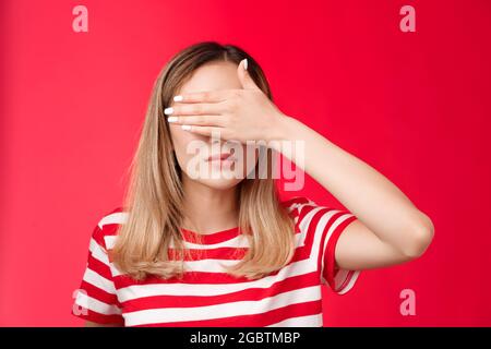 Ernst aussehende intensive asiatische Frau decken Sicht, halten Sie Handfläche auf die Augen nicht sehen schlechte Szene konzentriert aussehen angespannt und unter Druck stehen roten Hintergrund Stockfoto