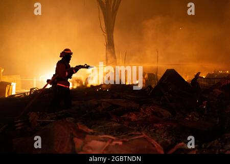 Ein Feuerwehrmitglied löscht die Überreste eines Gebäudes, das am 4. August 2021 in Greenville, CA, niedergebrannt ist. Das Dixie-Feuer zerstörte die Stadt am Mittwoch. (Foto von Daniel Brown/Sipa USA) Stockfoto