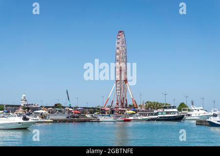 Batumi, Georgia - 2. Juli 2021: Batumi Coastline. Beliebte georgische Urlaubsstadt am Schwarzen Meer. Panoramablick auf das Riesenrad, den alphabetischen Turm, Wolkenkratzer und den Strand vom Meer aus. Stockfoto