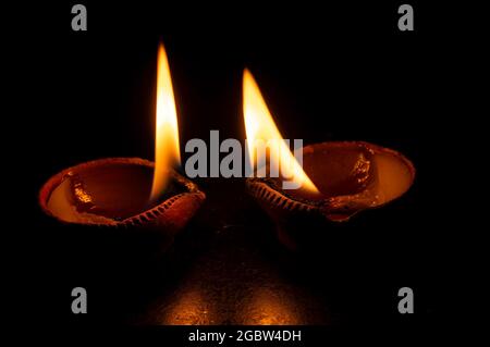 Seitenansicht von Kerzen oder Diyas, Deepawali Lichter in der Nacht. Dunkles Hintergrundbild. Stockfoto