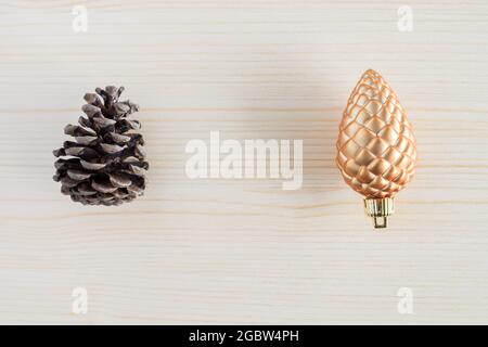 Tannenzapfen auf Holzhintergrund. Gegensätze Konzept. Neu versus alt, natürlich versus künstlich. Stockfoto