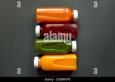 Frische Säfte oder Smoothies von Obst und Gemüse in Flaschen auf grauem Hintergrund. Das Konzept einer gesunden Ernährung, Ernährung oder Entgiftung. Stockfoto