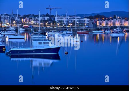 Wunderschöne Aussicht am frühen Morgen auf Boote und Yachten im West Pier des berühmten Hafens von Dun Laoghaire während der blauen Stunde vor Sonnenaufgang, Dublin, Irland Stockfoto