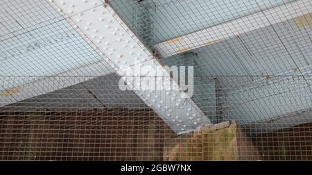 Unterseite der Metalleisenbahnbrücke mit Muttern und Schrauben und Taubennetz Stockfoto