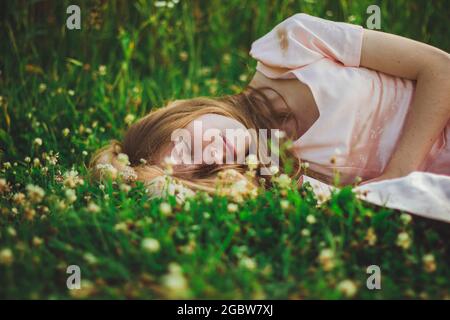 Foto einer schönen schlafenden Frau im Dreschfild mit Wildblumen Stockfoto