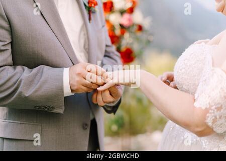 Der Bräutigam legt den Ring auf die Hand der Braut. Nahaufnahme Stockfoto