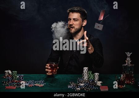 Bärtiger Casino Spieler Mann, der Poker auf dem grünen Tisch spielt Stockfoto