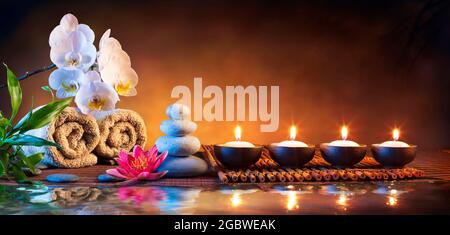 Spa Massage Steine Mit Kerzen Und Handtücher Auf Bambusmatte - Meditationskonzept Stockfoto