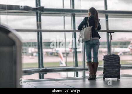 Reisetourist wartet am Flughafenfenster auf stornierten verspäteten Flug Urlaub. Nicht erkennbare Frau von hinten, die anschaut Stockfoto