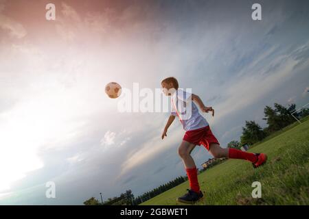 8 Jahre altes Kind spielt Fußball auf dem Spielfeld. Stockfoto