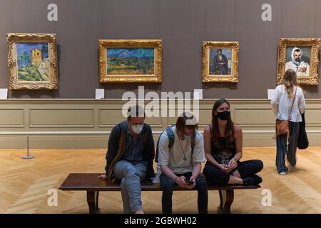 Menschen sitzen im Metropolitan Museum of Art mit Paul Cezanne Gemälden dahinter Stockfoto
