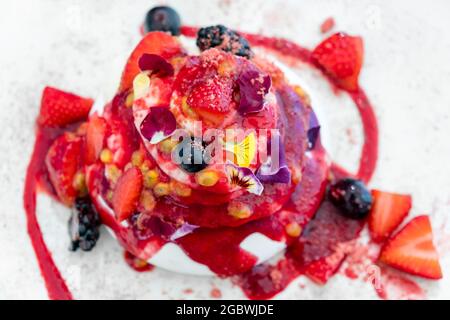 Gourmet-Erdbeer-Pavlova-Kuchen mit frischen Beeren und Schichten von Schlagsahne und Baiser auf einem Teller serviert, Stockfoto
