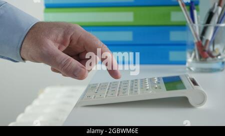 Geschäftsmann, der mit Rechnungen arbeitet, macht Finanzberechnungen mit Adding Machine. Berechnung von Buchungsgebühren und Steuern. Stockfoto