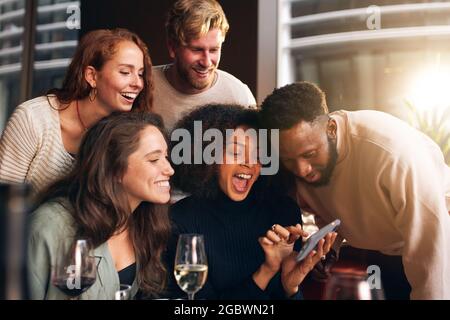 Freunde, die Fotos am Telefon in der Bar ansehen Stockfoto