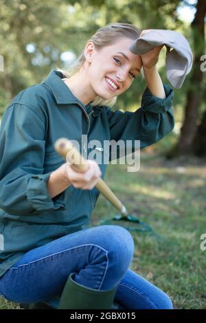 Junge Farmerin reinigt Rechen trockenes Gras Stockfoto